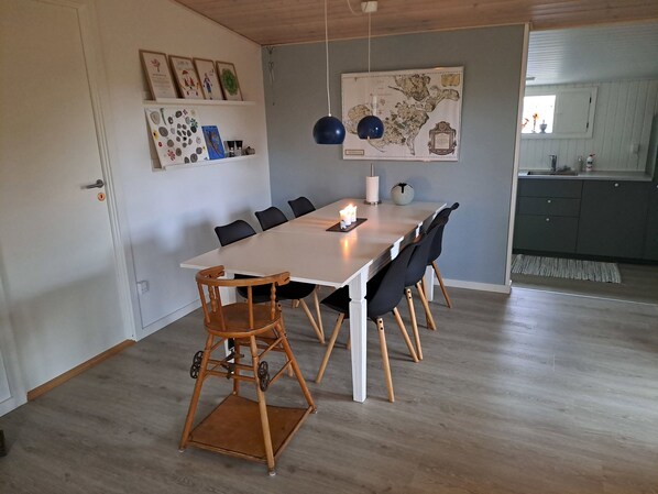 Un comedor con una mesa larga, sillas, un mapa en la pared y una cocina al fondo.