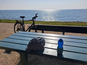 Una mesa con un casco, una botella de agua, una bicicleta y vista al mar.
