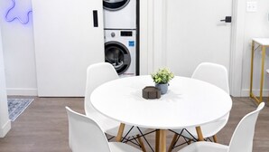 A modern kitchen with a built-in washer and dryer, a white dining table with four chairs, and a small plant on the table. - Apartment in Spokane (Spokane)