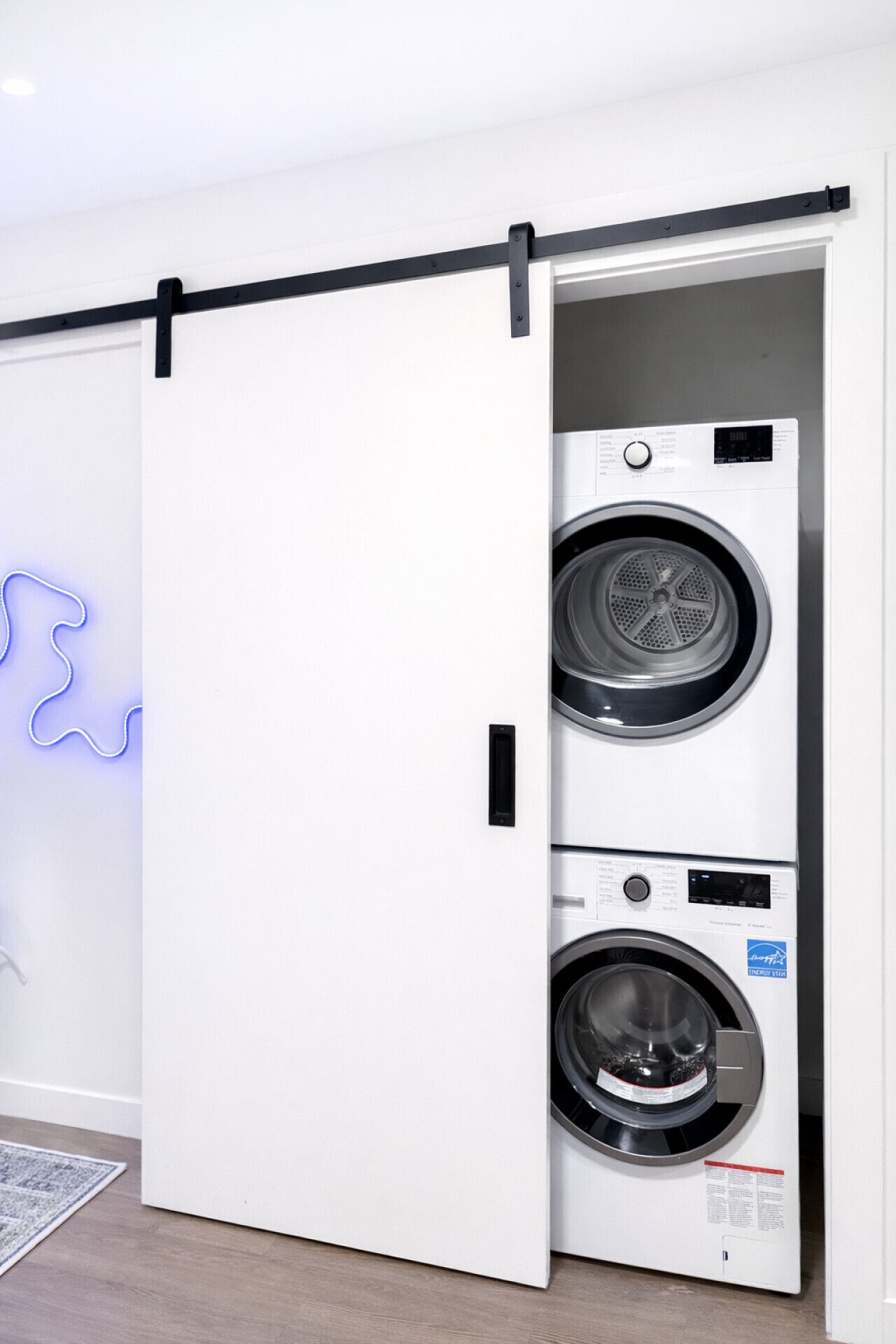 A modern laundry room with a wall-mounted dryer and a large sliding door.