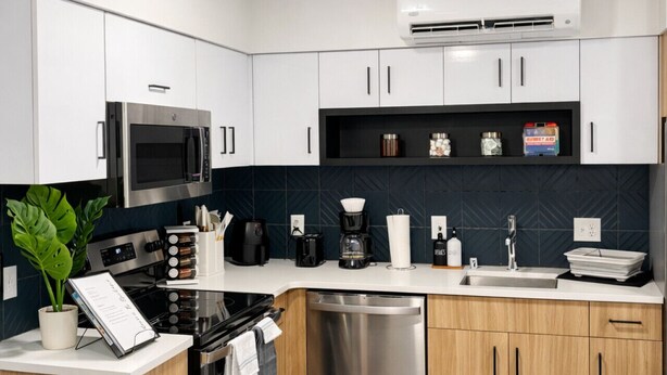 A modern kitchen with white cabinets, a stainless steel stove, a microwave, a dishwasher, and a coffee maker. - Apartment in Spokane (Spokane)