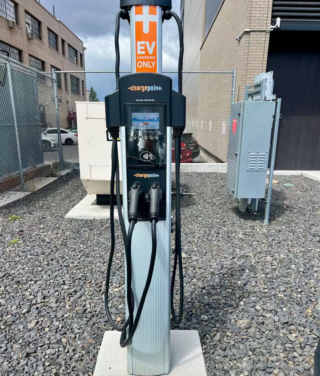 An EV charging station with a sign indicating it's for EV only, a digital display, and a cable for charging.