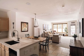 A spacious kitchen with a central island, a dining area with a table and chairs, a living room with a sofa and a TV, and large windows providing natural light. - Lakefront Keystone Escape | Near Slopes & Trails (Keystone)