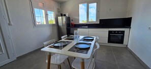 Een kleine keuken met een eettafel gedekt voor twee personen, een koelkast en een fornuis.