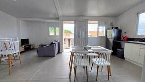 Een moderne keuken met witte kastjes, een eettafel met stoelen, een bank en een televisie.