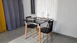 A dining area with a black table and chairs, a glass pitcher, and a small plant on the table. - La Fleur Doré studio - Vauclin (Le Vauclin)