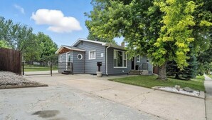 Une maison à deux étages avec un jardin devant, une allée et une clôture en bois.