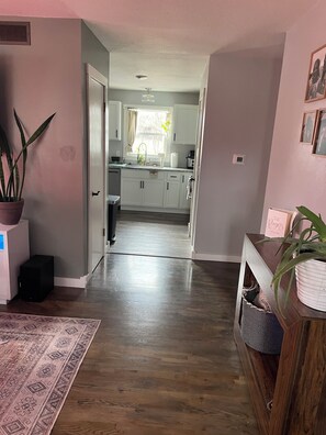A modern kitchen with white cabinets, a window with a curtain, and a potted plant on the left. - Spacious 4-bedroom Sturgis Motorcycle Rally rental with AC located in  Spearfish (Spearfish)