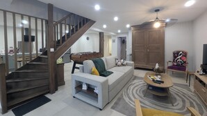 A spacious living room with a staircase, a sofa, a coffee table, and a TV.
