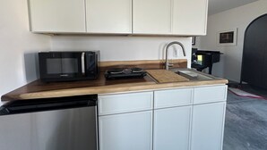 Cuina compacta amb armaris blancs, microones negre, un rentaplat i una pica.