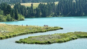 Un llac envoltat de turons boscosos, amb gent caminant i fent caiac.