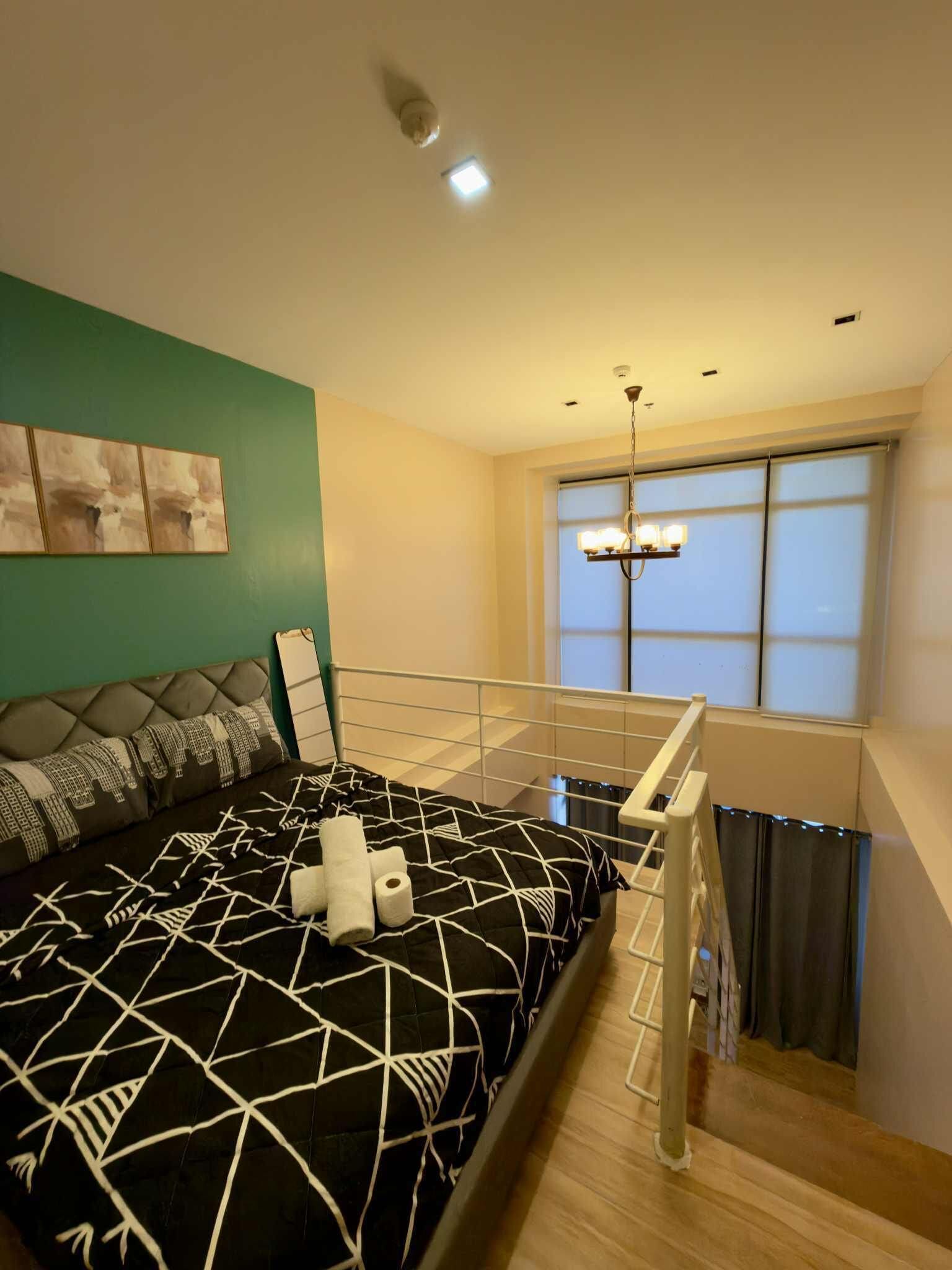 A modern bedroom with a bed, a chandelier, and a window.