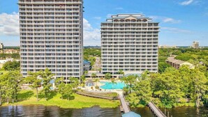 Ein Hochhaus mit mehreren Balkonen, einem Schwimmbad und einem Steg, der sich in ein Gewässer erstreckt.
