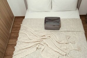 A neatly made bed with a grey bag on it, a herringbone-patterned bedspread, and a crocheted blanket. - Shore CIty Central Stay Apartments (Pasay City)