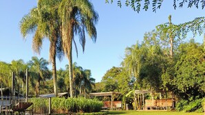 A well-maintained grassy area with palm trees and a wooden pergola. - Exclusive Cabin in La Aventura Complex (Posadas)