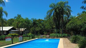 A rectangular swimming pool with a clear blue water surface, surrounded by a stone deck and a metal fence. - Exclusive Cabin in La Aventura Complex (Posadas)