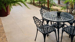 An outdoor patio area with a covered seating area, including a round table and chairs, surrounded by potted plants and a pathway leading to a garden. - Exclusive Cabin in La Aventura Complex (Posadas)