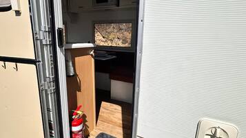 An RV interior with a kitchenette, a small window, and a fire extinguisher.