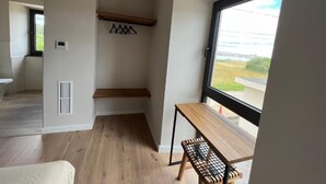 A modern room with a wooden bench, a small table, and a large window offering a view of the outdoors.