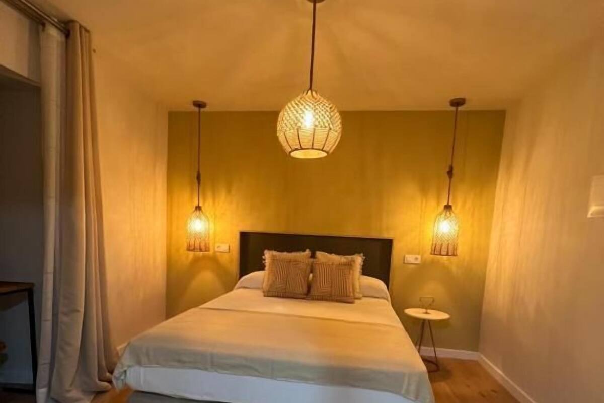 Ein Schlafzimmer mit einem großen Bett, zwei Nachttischlampen und einer Deckenleuchte.