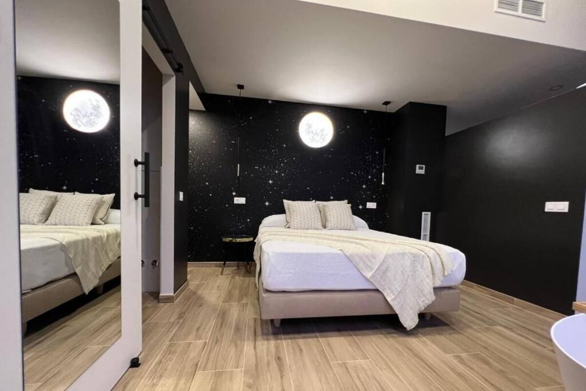 Ein Schlafzimmer mit zwei Betten, einem Wanddesign mit Sternen und einer Monddekoration.