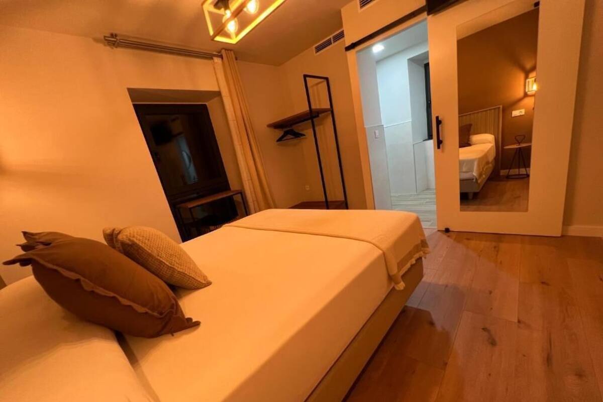 Ein Schlafzimmer mit Bett, Kissen, einem Fernseher und einer Tür zu einem Badezimmer.