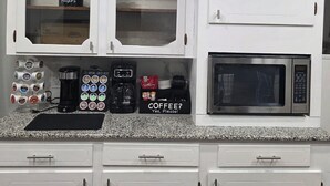 Una cocina con armarios blancos, una cafetera y un microondas.