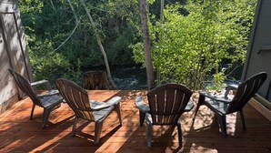 Eine Holzterrasse mit vier Adirondack-Stühlen, die auf eine natürliche Landschaft ausgerichtet sind.
