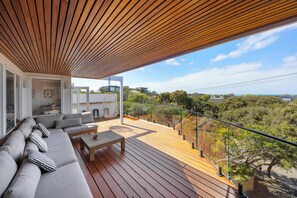 A modern outdoor deck with a wooden ceiling, a sofa set, and a view of the surrounding landscape. - Tuckey Terrace | Heated Pool, Spa & Bay Views (Sorrento)