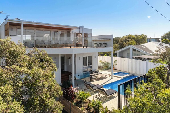 A modern two-story house with a balcony, a swimming pool, and a garden area. - Tuckey Terrace | Heated Pool, Spa & Bay Views (Sorrento)