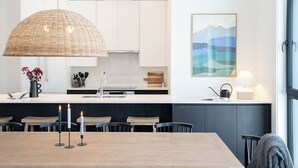 A modern kitchen with white cabinets, a large island with a sink, and a dining area with a table and chairs.