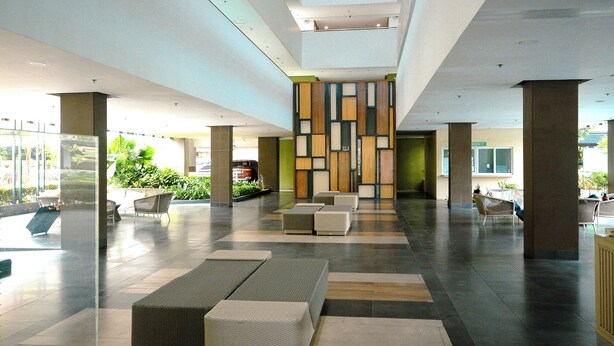 Eine geräumige Lobby mit hoher Decke, großen Fenstern und einer zentralen Sitzecke.