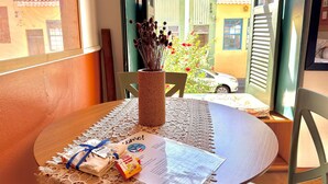A round table with a lace tablecloth, a vase with dried flowers, a menu, and a small gift box. - Rememorar 01 (Salvador)