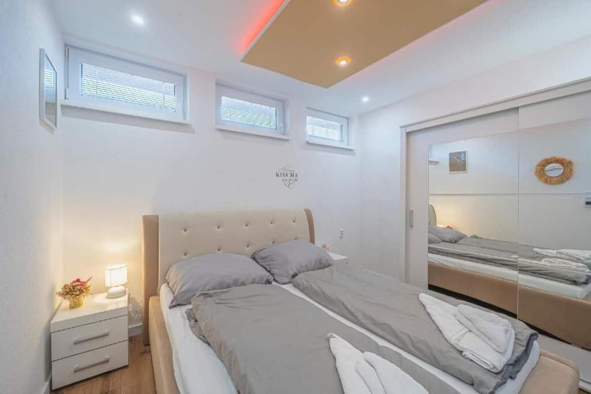 A bedroom with a bed, bedside tables, a mirror, and a ceiling light.