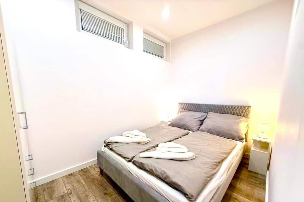 A small, modern bedroom with a single bed, a bedside table, and a nightstand.