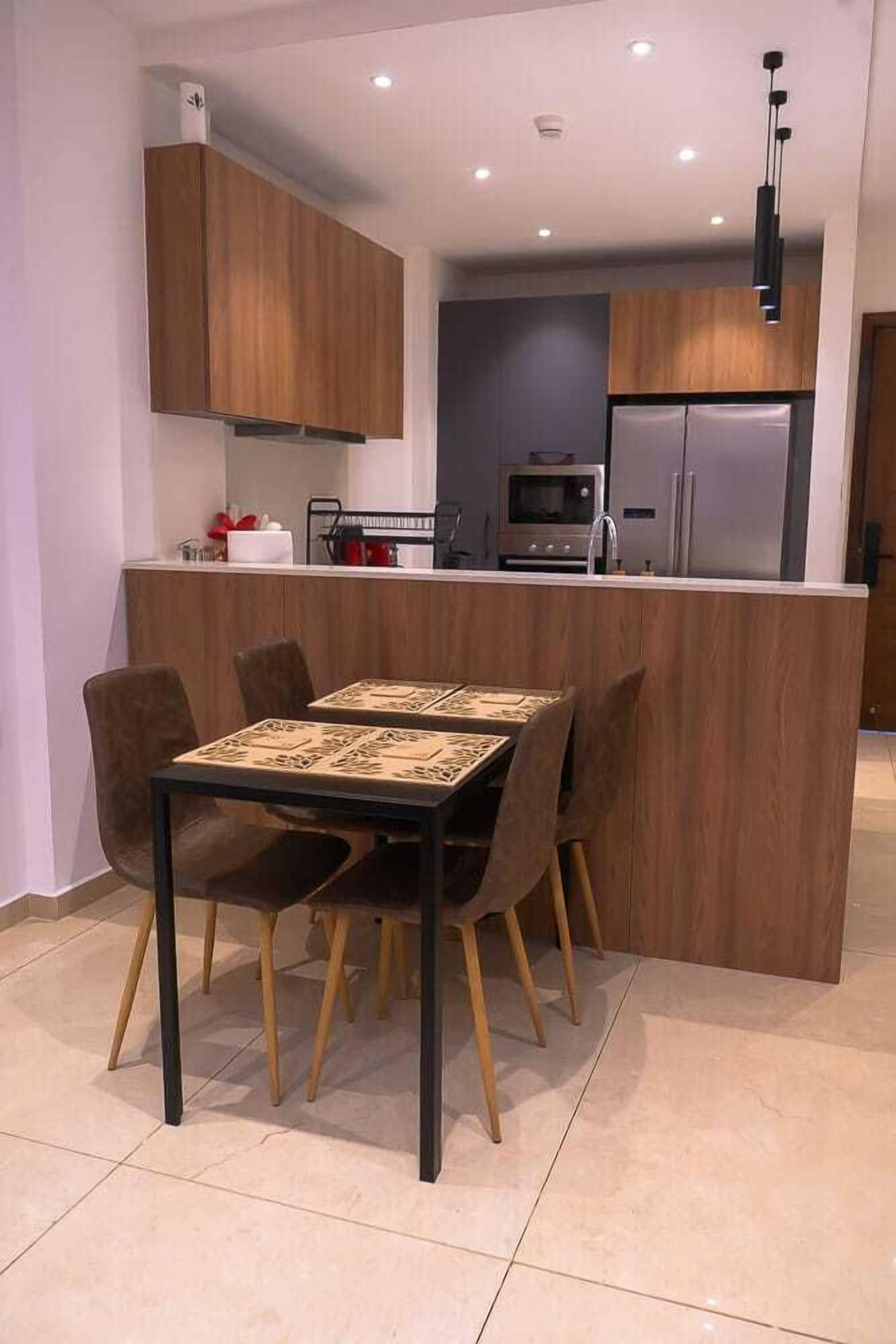 Une cuisine moderne avec des meubles en bois, un îlot central et un coin repas comprenant une table et des chaises.