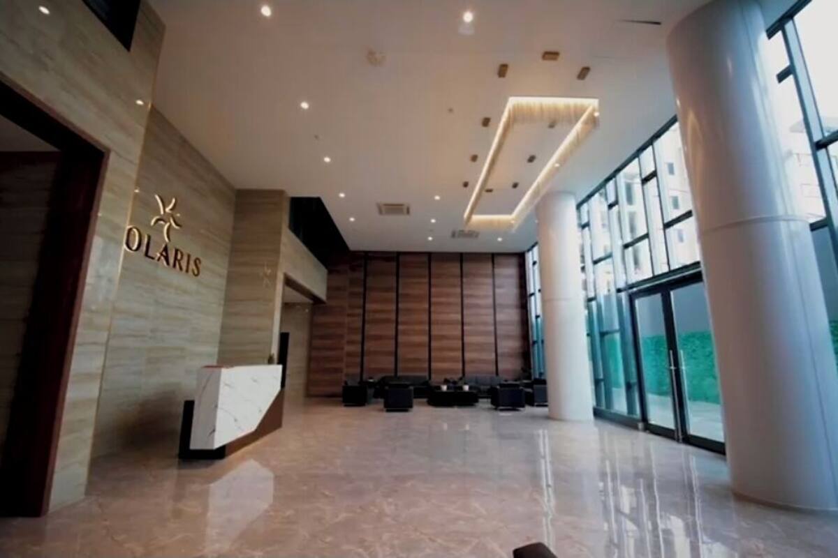 Een moderne hotel lobby met een receptiebalie, grote ramen en een schone, gepolijste vloer.