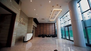 A modern hotel lobby with a reception desk, large windows, and a clean, polished floor. - Solaris Apartments luxury by Cozy (Accra)