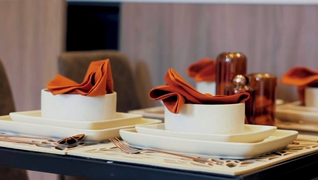 A dining table set with white plates, bowls, and folded napkins.