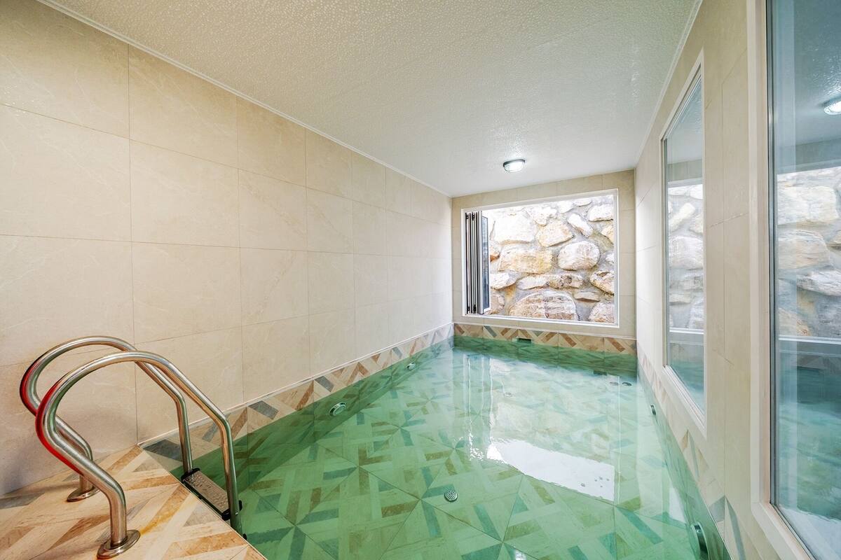 Une piscine avec un mur en pierre et une fenêtre.