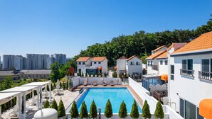 A rooftop pool area with a clear view of the city skyline, surrounded by modern buildings and greenery. - Gyeongju Awesomeway Pool Villa (Gyeongju)