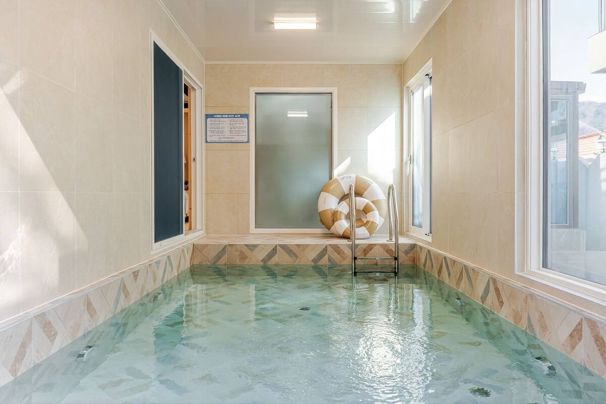 Une piscine avec un mur en verre, une porte et un panneau fixé au mur.