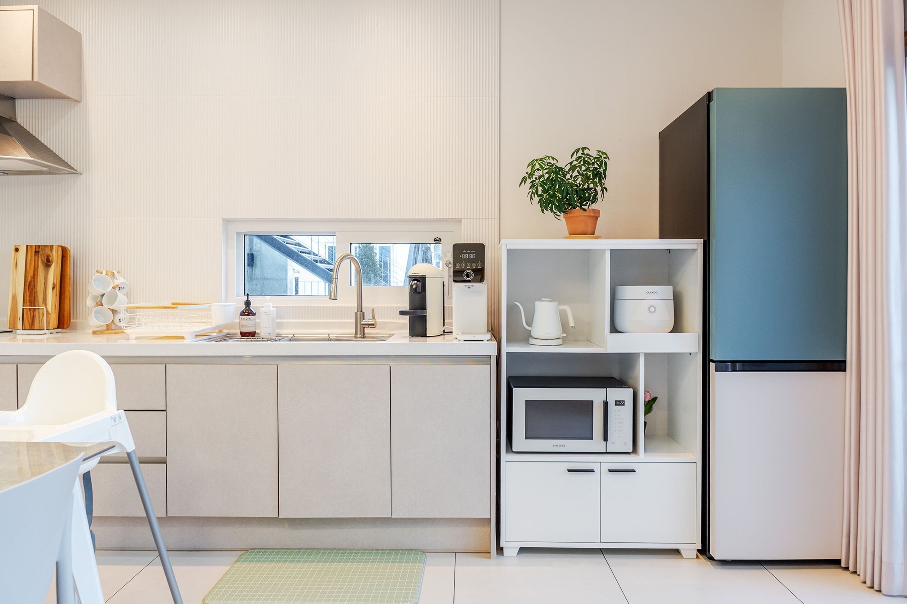Una cocina moderna con microondas, cafetera y una planta en la encimera.