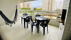 Un balcón con mesa y sillas, una hamaca y vistas de edificios altos.