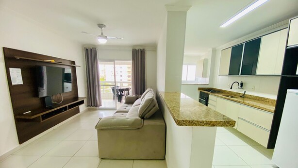 Una sala de estar moderna con un sofá, un televisor de pantalla plana y una zona de comedor con mesa y sillas.