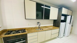 Una cocina moderna con estufa a gas, horno, lavamanos y armarios blancos.