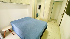Un dormitorio pequeño con una cama individual, una mesita y un armario.