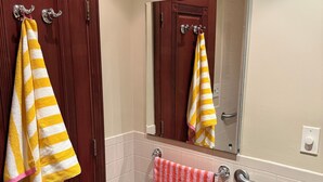 A bathroom with a wooden door, a mirror, a towel rack with striped towels, a handrail, and a blue tiled floor. - Huge 1BR with central AC+laundry in quiet area MINUTES from Ridgewood & Bushwick (New York)