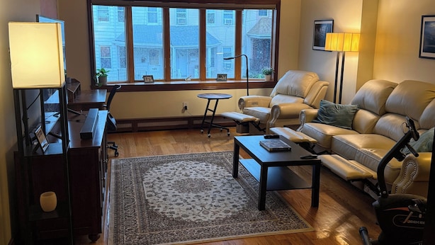 A spacious living room with a large window, a leather sofa, a coffee table, and a treadmill. - Huge 1BR with central AC+laundry in quiet area MINUTES from Ridgewood & Bushwick (New York)