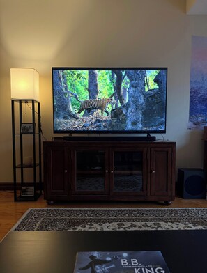Un téléviseur posé sur un meuble en bois, une lampe et un tableau encadré sur un pied.
